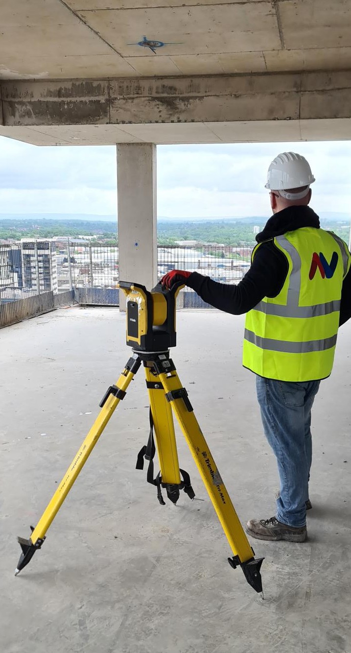 AV engineer using a yellow Trimble total station on site
